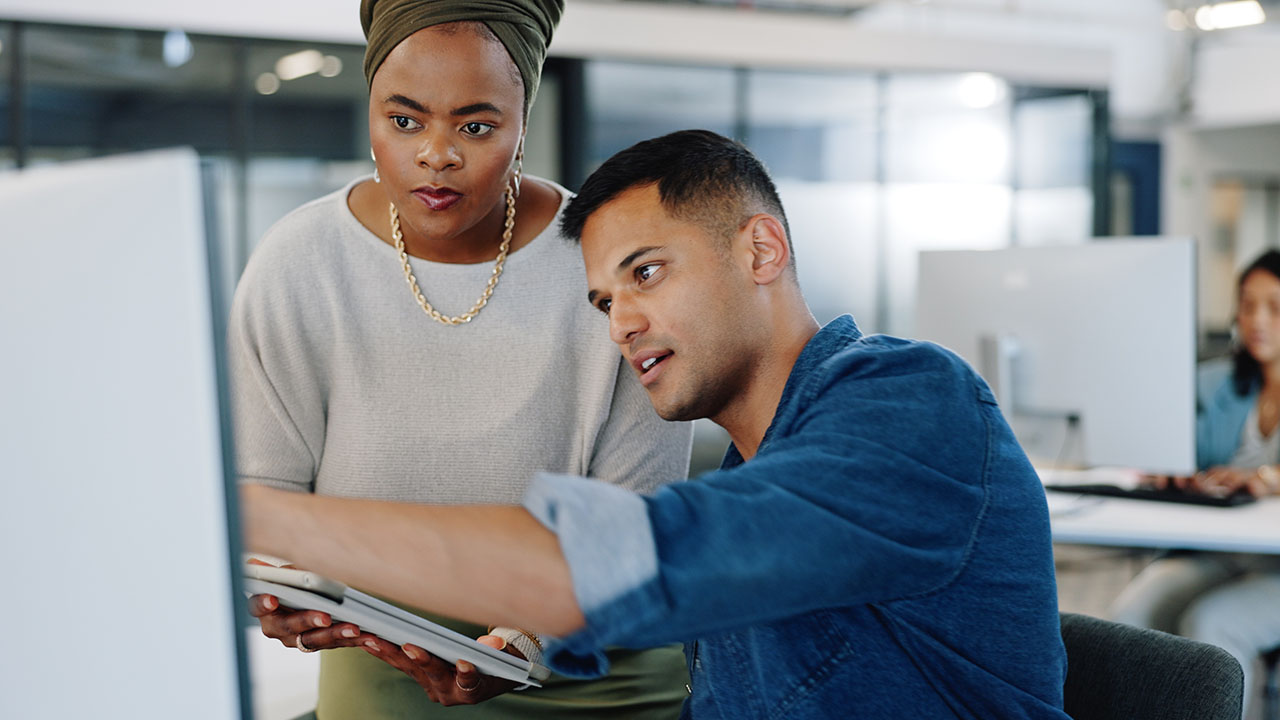 Coworkers looking at a computer monitor discussing plans